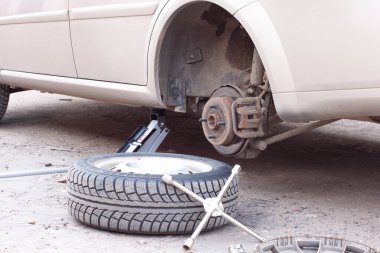 Arabadaki tekerlekleri değiştiriyorum. Arabayı krikoyla kaldırıyorum.