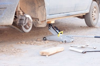 Arabadaki tekerlekleri değiştiriyorum. Arabayı krikoyla kaldırıyorum.