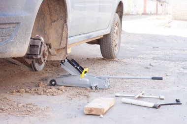 Arabadaki tekerlekleri değiştiriyorum. Arabayı krikoyla kaldırıyorum.