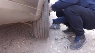 Arabanın tekerleğini değiştiriyorum. vidaları sökmek ve fındıkları sıkmak.