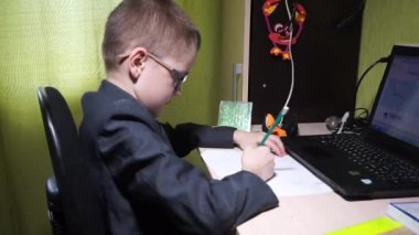 Ceketli bir çocuk ödevini yapar. Bir kağıt parçasına kurşun kalemle yazıyor. Uzak bir sitedeki yaşam