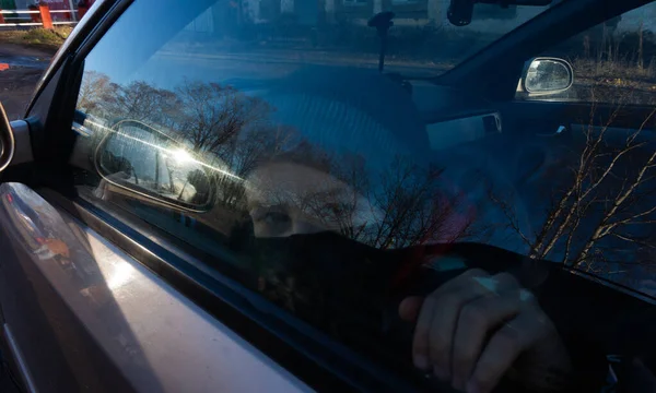 a boy in a black mask behind a car window