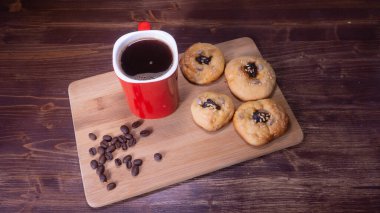 Kurabiye ve kahve çekirdekli kırmızı kahve kupası.