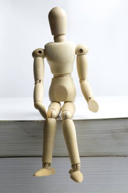 Ahşap adam kitap oturur.