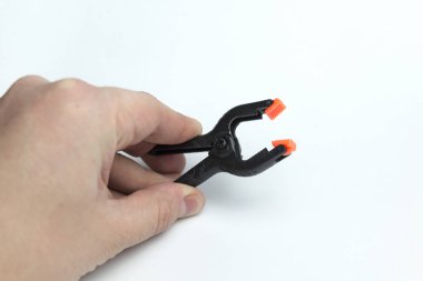 Beyaz bir arka planda bir clothespin tutan el.