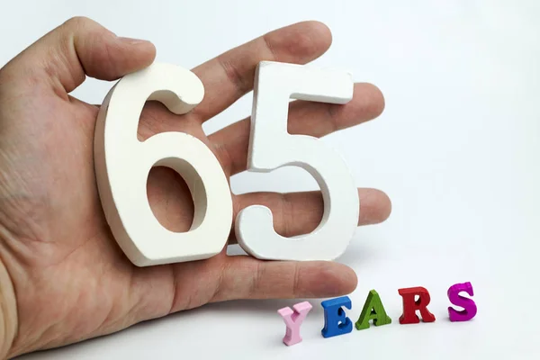 Hand holds a figure of sixty-five. — Stock Photo, Image