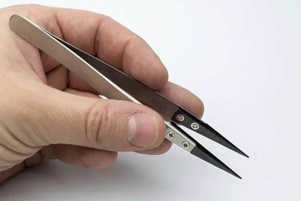 Hand holding a pair of tweezers. — Stock Photo, Image