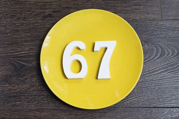 Число шістдесят сім на жовтій тарілці . — стокове фото