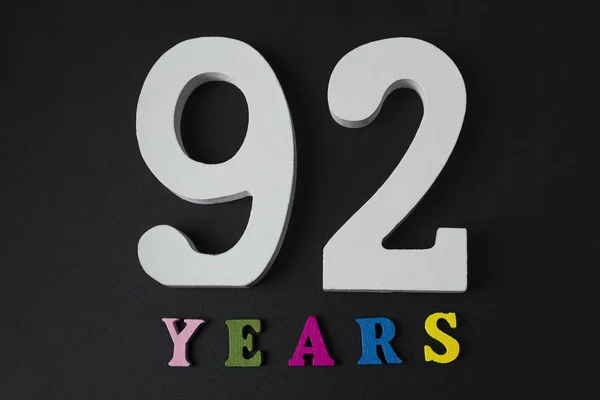 Buchstaben und Zahlen zweiundneunzig Jahre auf schwarzem Hintergrund. — Stockfoto