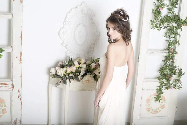 Fille dans une robe blanche avec des fleurs dans la maison . — Photo