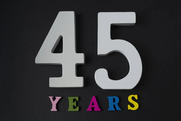 Buchstaben und Zahlen fünfundvierzig Jahre auf schwarzem Hintergrund. — Stockfoto