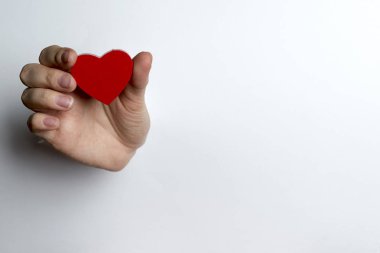 Beyaz bir arka plan üzerinde bir kalp tutan el.