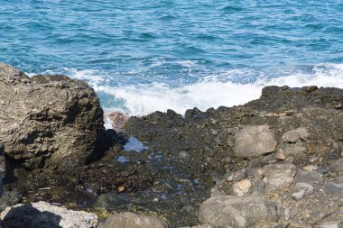 Bir sprey şekillendirme Taşlı bir kumsalda kırma dalgalar. Dalga ve su sıçramalarına sahilde. Dalgalar kayalar üzerine çökmesini.