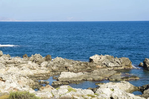 Le onde si infrangono su una spiaggia rocciosa, formando uno spray. Onde e spruzzi sulla spiaggia. Onde che si infrangono sulle rocce . — Foto Stock