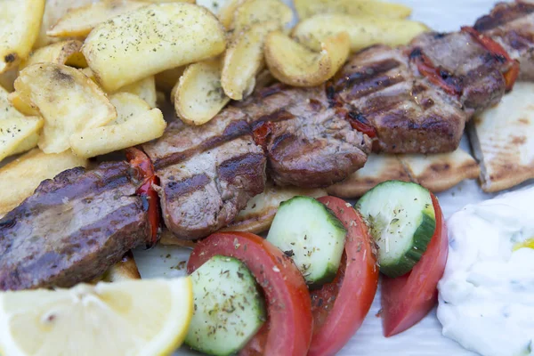 Izgara domuz biftek bir tavada, closeup görünümü sebze ve patates kızartması ile.