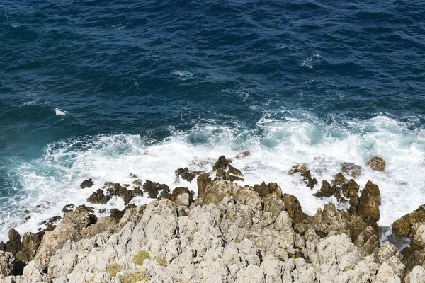 Las olas rompiendo en una playa pedregosa, formando un aerosol. Olas y salpicaduras en la playa. Olas chocando contra rocas . — Foto de Stock