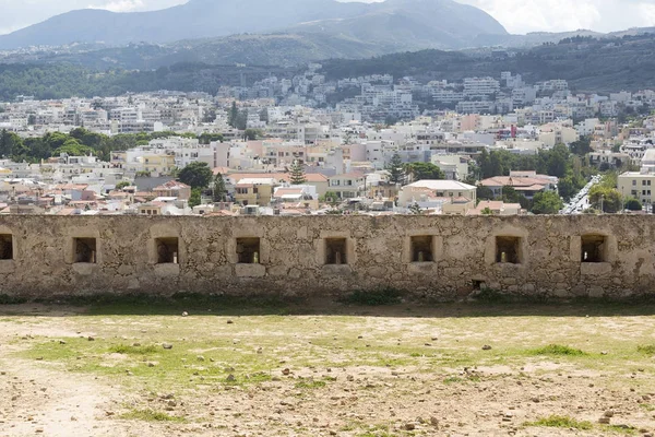 Vista del complejo Arquitectura griega Rethymno ciudad-puerto, construido por los venecianos, desde la altura del castillo de Fortezza fortaleza en la colina Paleokastro. Techos de tejas rojas y montañas de fondo. Creta . — Foto de Stock