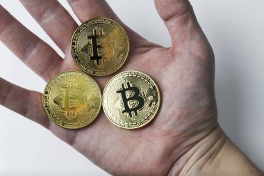 El üç bitcoin beyaz bir arka plan üzerinde tutar..