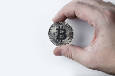Gümüş bir bitcoin beyaz bir arka plan üzerinde tutan el.