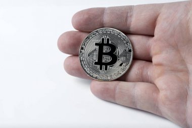 Gümüş bir bitcoin beyaz bir arka plan üzerinde tutan el.