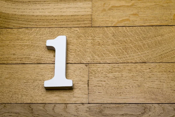 Nummer een op de houten, parketvloer. — Stockfoto