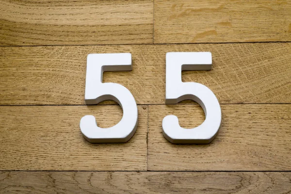 The numbers fifty-five on a wooden parquet floor.