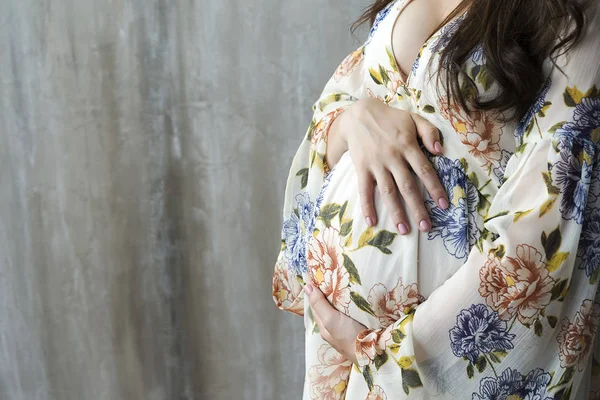 O abdômen de uma mulher grávida em fundo cinza . — Fotografia de Stock