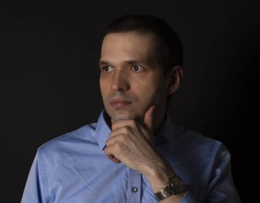 Siyah arka planda mavi gömlekli bir adam. Mavi gömlekli yakışıklı bir iş adamı..