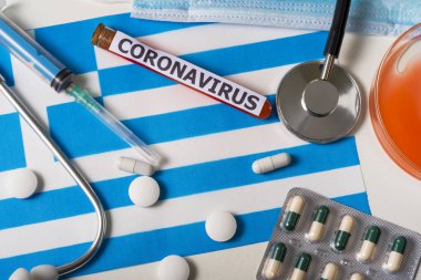 Coronavirus, ncov konsepti. Üst düzey koruyucu solunum maskesi, steteskop, şırınga, Yunanistan bayrağında haplar. Yeni bir Çin Coronavirüsü salgını.