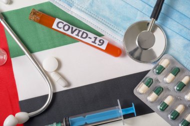 Coronavirus, Covid-19 konsepti. Üst düzey koruyucu solunum maskesi, steteskop, şırınga, Birleşik Arap Emirlikleri bayrağındaki haplar. Yeni bir Çin Coronavirüsü salgını.
