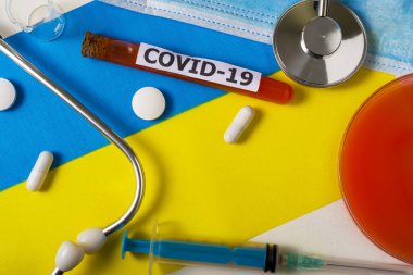 Coronavirus, Covid-19 konsepti. Üst düzey koruyucu solunum maskesi, steteskop, şırınga, Ukrayna bayrağında tabletler. Yeni bir Çin Coronavirüsü salgını.
