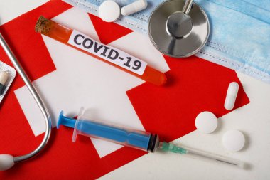 Coronavirus, Covid-19 konsepti. Üst düzey koruyucu solunum maskesi, steteskop, şırınga, İsviçre bayrağında haplar. Yeni bir Çin Coronavirüsü salgını.
