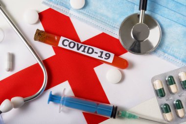 Coronavirus, Covid-19 konsepti. Üst düzey koruyucu maske, steteskop, şırınga, İngiltere bayrağında haplar. Yeni bir Çin Coronavirüsü salgını.