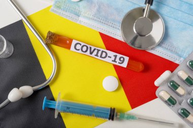 Coronavirus, Covid-19 konsepti. Üst düzey koruyucu maske, steteskop, şırınga, Belçika bayrağında haplar. Yeni bir Çin Coronavirüsü salgını.