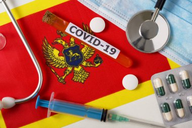Coronavirus, Covid-19 konsepti. Üst düzey koruyucu solunum maskesi, steteskop, şırınga, Karadağ bayrağında haplar. Yeni bir Çin Coronavirüsü salgını.