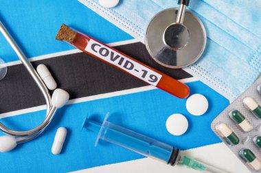 Coronavirus, COVid-19 konsepti. Botswana bayrağında koruyucu bir nefes maskesi, steteskop, şırınga ve tabletler görünüyor. Yeni bir Çin Coronavirüsü salgını.