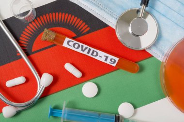 Coronavirus, COVid-19 konsepti. Malawi bayrağındaki koruyucu bir maske, steteskop, şırınga ve tabletler yukarıdan görülebilir. Yeni bir Çin Coronavirüsü salgını.