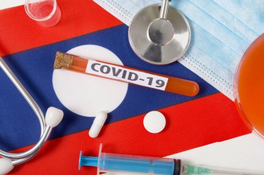 Coronavirus, COVid-19 konsepti. Üst düzey koruyucu solunum maskesi, steteskop, şırınga, Laos bayrağında tabletler. Yeni bir Çin Coronavirüsü salgını.