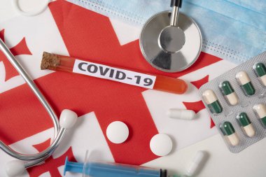 Coronavirus, COVid-19 konsepti. Üst düzey koruyucu maske, steteskop, şırınga, Georgia bayrağında tabletler. Yeni bir Çin Coronavirüsü salgını.