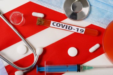 Coronavirus, COVid-19 konsepti. Üst düzey koruyucu solunum maskesi, steteskop, şırınga, Avusturya bayrağında tabletler. Yeni bir Çin Coronavirüsü salgını.