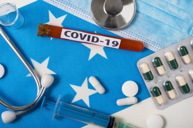 Coronavirus, COVid-19 konsepti. Üst düzey koruyucu solunum maskesi, steteskop, şırınga, mikronezya bayrağında tabletler. Yeni bir Çin Coronavirüsü salgını.