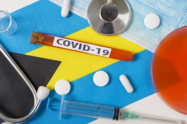 Coronavirus, COVid-19 konsepti. Üst düzey koruyucu solunum maskesi, steteskop, şırınga, Bahamalar 'ın bayrağında haplar. Yeni bir Çin Coronavirüsü salgını.
