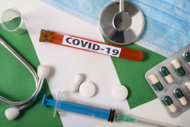 Coronavirus, COVid-19 konsepti. Üst düzey koruyucu solunum maskesi, steteskop, şırınga, Nijerya bayrağında tabletler. Yeni bir Çin Coronavirüsü salgını.