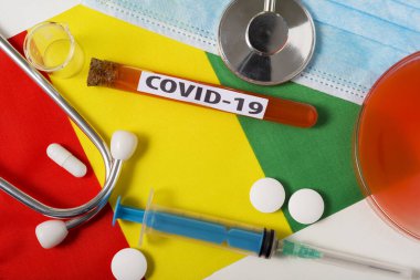 Coronavirus, COVid-19 konsepti. Üst düzey koruyucu solunum maskesi, steteskop, şırınga, Gine bayrağında tabletler. Yeni bir Çin Coronavirüsü salgını.