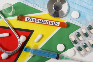 Coronavirus, NCoV konsepti. Üst düzey koruyucu solunum maskesi, steteskop, şırınga, Guyana bayrağında haplar. Yeni bir Çin Coronavirüsü salgını.
