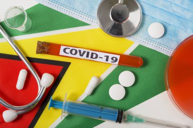 Coronavirus, COVid-19 konsepti. Üst düzey koruyucu solunum maskesi, steteskop, şırınga, Guyana bayrağında haplar. Yeni bir Çin Coronavirüsü salgını.
