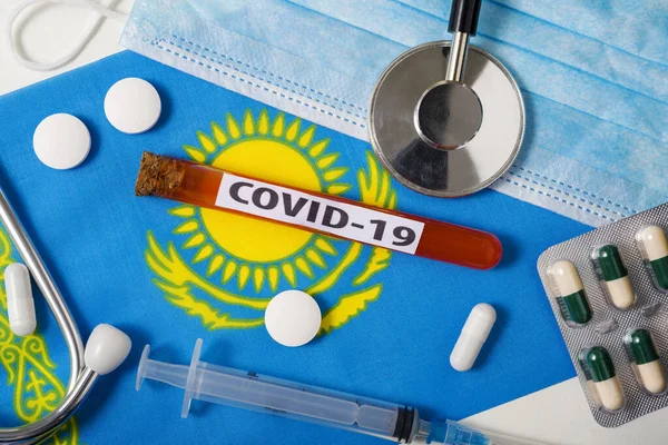 Coronavirus, COVid-19 konsepti. Üst düzey koruyucu solunum maskesi, steteskop, şırınga, Kazakistan bayrağında tabletler. Yeni bir Çin Coronavirüsü salgını.