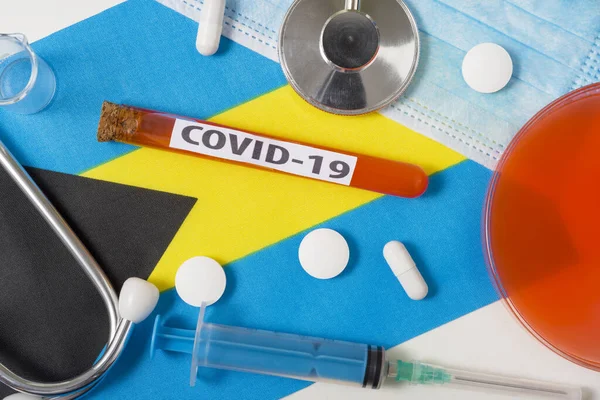 Coronavirus, COVid-19 konsepti. Üst düzey koruyucu solunum maskesi, steteskop, şırınga, Bahamalar 'ın bayrağında haplar. Yeni bir Çin Coronavirüsü salgını.