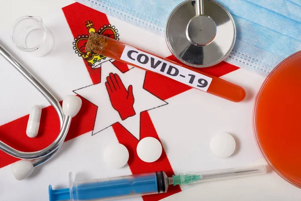 Coronavirus 概念Covid 俯瞰保护呼吸面罩 听诊器 注射器 北爱尔兰国旗上的药片 中国头孢病毒的新爆发 — 图库照片