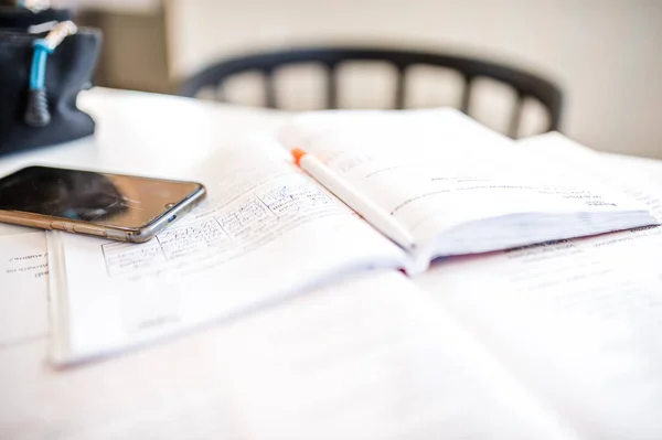 open book and a notebook on the table with a phone the topic of distance learning of students in quarantine